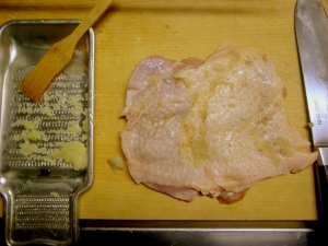 包丁の先で皮に穴を開け、すりおろしニンニク、塩、胡椒をすり込む