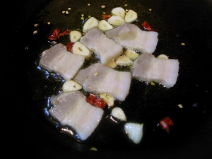 オリーブオイルでニンニク、唐辛子、豚肉を炒める