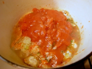 トマト缶も加える、プラス塩、胡椒少々、コンソメキューブをひとつ入れる