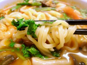 濃いスープがからんだ極太麺をパクチーと一緒に
