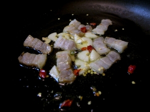オリーブオイルで塩豚、ニンニク、唐辛子を炒める