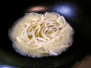 スープの残りに少量のめんつゆを入れ、スライスしたタマネギを煮る