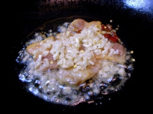 塩豚をじっくり炒めてラードが出たら、ニンニク、生姜、唐辛子を入れる