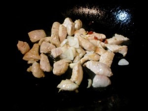 サラダ油で鶏胸肉を炒めて、ニンニクと唐辛子を入れる
