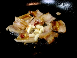 塩豚が焼けたらニンニクと唐辛子を入れる