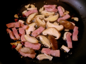 オリーブオイル、ニンニク、唐辛子、ベーコン、椎茸と炒めていく