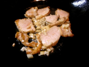 ごま油で豚もも肉を炒め、焼き色が付いたらニンニクのみじん切りを入れる