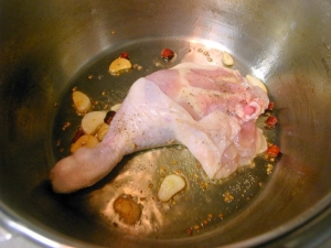 オリーブオイルにニンニク、唐辛子で鳥もも肉の表面を焼く