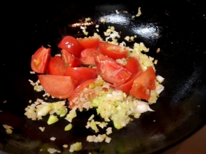 生姜と長ネギのみじん切りを炒めたらトマトを入れる