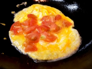 きれいにした中華鍋に溶き卵を入れ、固まりだしたらトマトを入れる