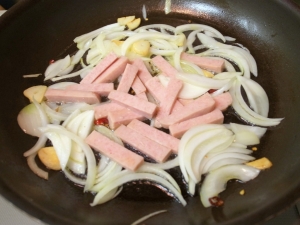 オリーブオイル、ニンニク、唐辛子、タマネギ、スパムを炒める