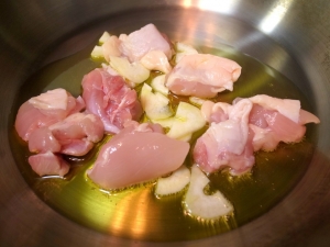 オリーブオイル、ニンニク、鶏もも肉を炒める