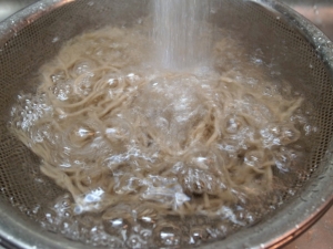 茹であがった蕎麦を流水で洗う