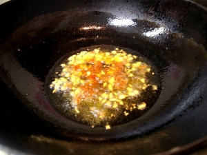 中華鍋にごま油を入れ、ニンニクと豆板醤を炒める
