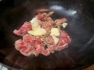 中華鍋を熱して牛肉、ニンニク、唐辛子を炒める