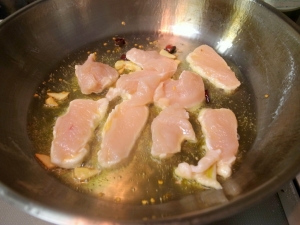 オリーブオイル、ニンニク、唐辛子、鶏胸肉を炒める
