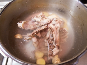 圧力鍋に、鶏ガラ、水、生姜を入れる
