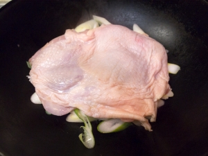 中華鍋に長ネギと鶏肉を入れ、水大さじ２を振りかけて火をつける