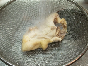 茹でた鶏ガラを水洗いする