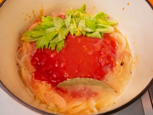 トマト缶、ローリエ、セロリの葉を加えて煮込む