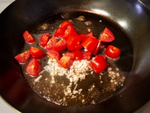 フライパンにミニトマト、にんにく、ビネガー、水を加えて加熱する