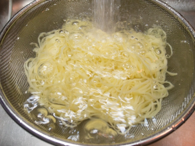 長めに茹でたパスタを流水で冷やす