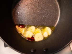 鍋でオリーブオイル、ニンニク、唐辛子を熱する