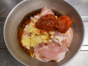 切り分けた鶏もも肉にニンニク、生姜、豆板醤、醤油、酒をもみ込む