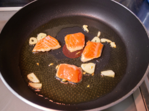 オリーブオイルでニンニクと鮭を炒める