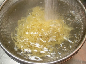 茹でたラーメンを流水で冷やす