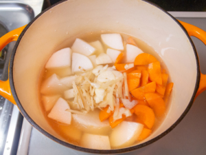 スープと根菜を鍋に入れて火をつける