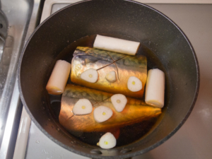 鍋にサバ、長ねぎ、ニンニク、醤油、みりん、酒、水を入れて火をつける