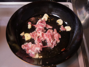 オリーブオイル、ニンニク、唐辛子、豚肉を炒める