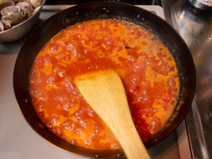 トマトを木べらで潰しながら煮詰める