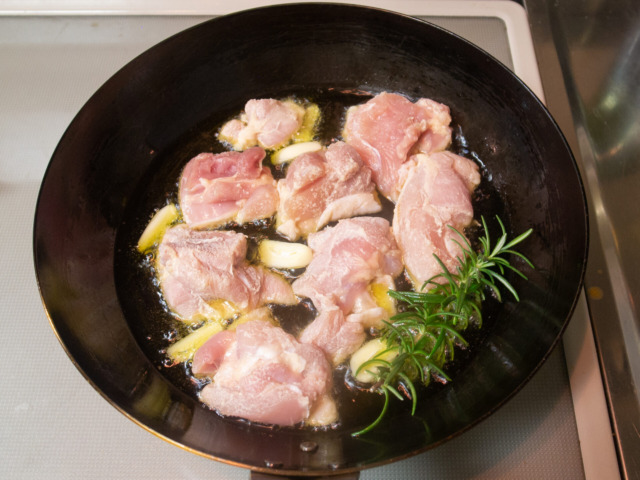 フライパンにオリーブオイル、ニンニク、ローズマリー、鶏肉を入れて火をつける