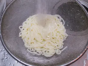 茹でたうどんを流水で冷やす