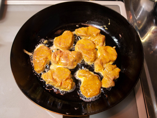 サラダ油を熱したフライパンで溶き卵をくぐらせた豚肉を焼く