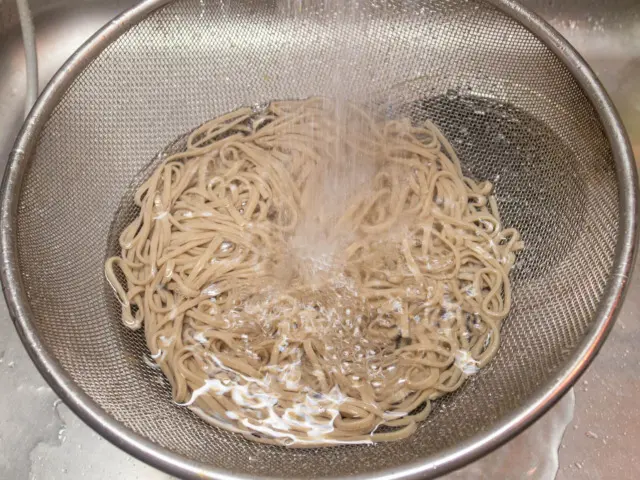 茹でた蕎麦を流水で洗う