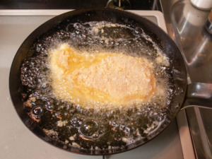 フライパンに油を熱してチキンカツを揚げる