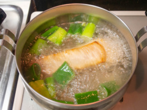 調理鍋に豚肉と水、長ねぎを入れて煮る