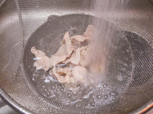 茹でた豚肉を流水で冷やす