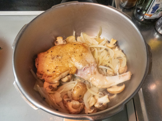 圧力鍋に炒めた玉ねぎ、マッシュルーム、鶏もも肉を入れる