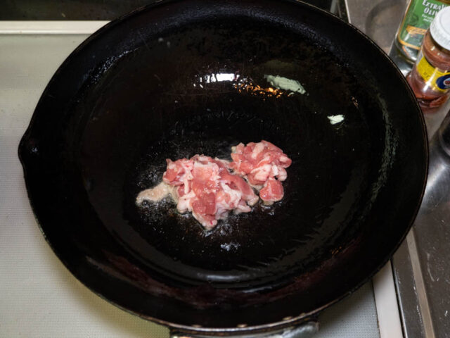 中華鍋にサラダ油を熱して豚肉を炒める写真