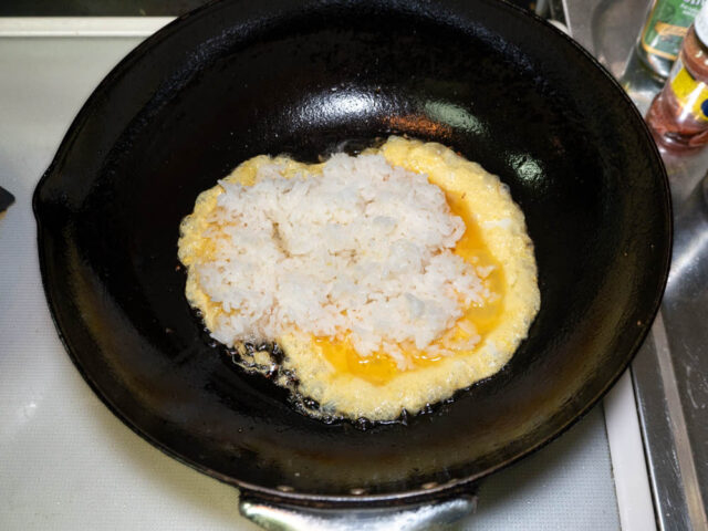 中華鍋に溶き卵とご飯を加えた写真