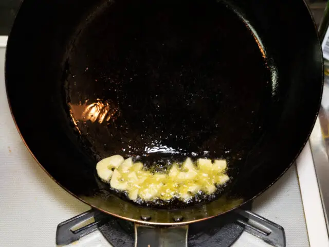 フライパンにオリーブオイルを熱してニンニクを炒める写真