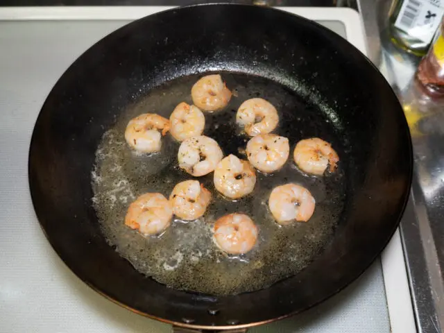 海老を炒めたフライパンにパスタの茹で汁を加えた写真