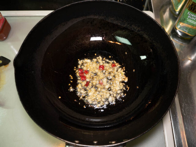 中華鍋にごま油、ニンニク、唐辛子を入れて加熱する写真