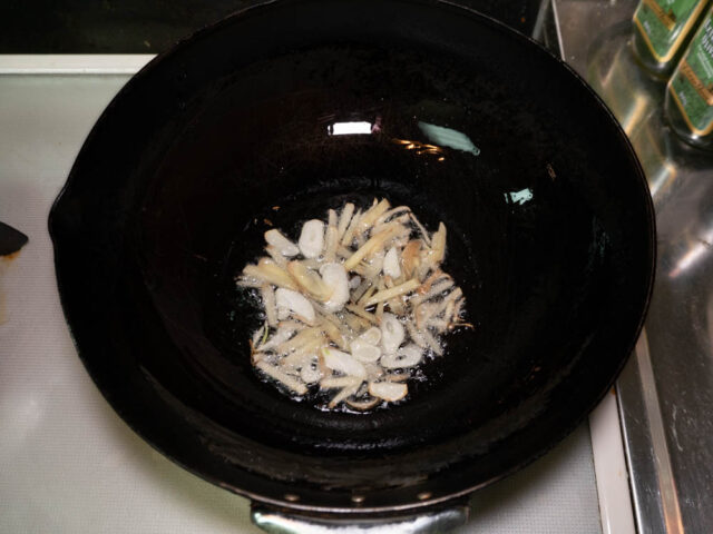 中華鍋にサラダ油を熱してニンニクと生姜を炒める写真