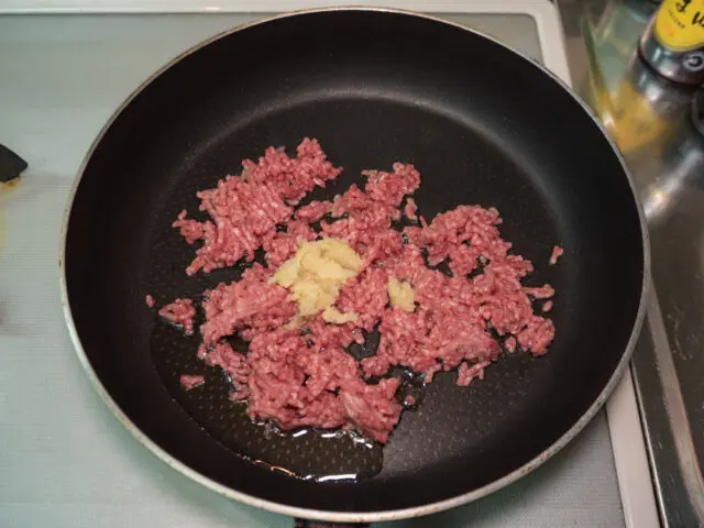 フライパンにサラダ油、挽肉、ニンニク、生姜を入れて炒める写真