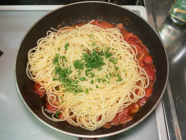 フライパンに茹で上がったパスタとパセリを加えた写真
